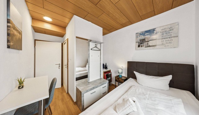 Cozy single room, flat-screen TV, and modern bathroom with shower. Ideal for singles and short stays – enjoy a relaxed atmosphere with warm wood accents and coastal charm.